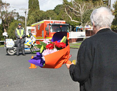 Local resident Merle Wedding brings flowers to the cordon near where Sgt. Don Wilkinson was shot dead. Photo / Glenn Jeffrey