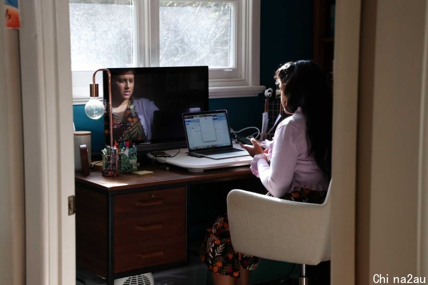 A woman at a home office looking at her phone 