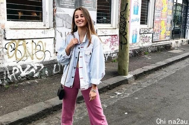 Girl standing on a street in front of a wall with graffiti