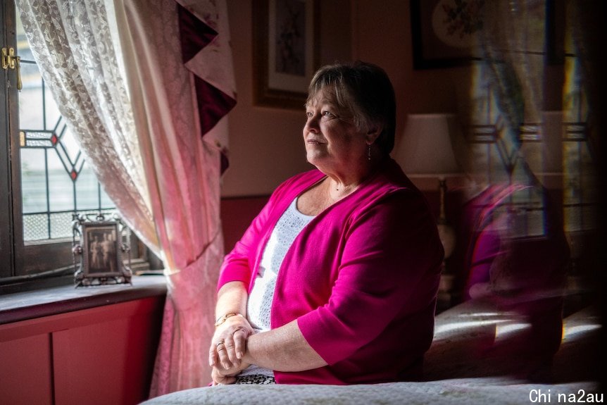 Val Stewart sits, looking out a window, her arms on her lap.