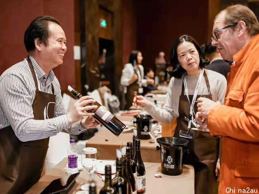 徐国荣（中）与丈夫许慧高（左）在葡萄酒展会上向客人介绍他们的“肯辛顿”葡萄酒。