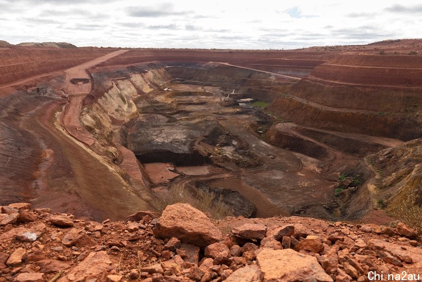 Massive hole in the ground with tiers of red dirt