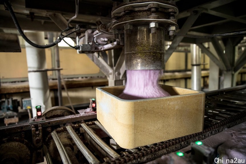 Pink rare earths product being loaded into container on production line