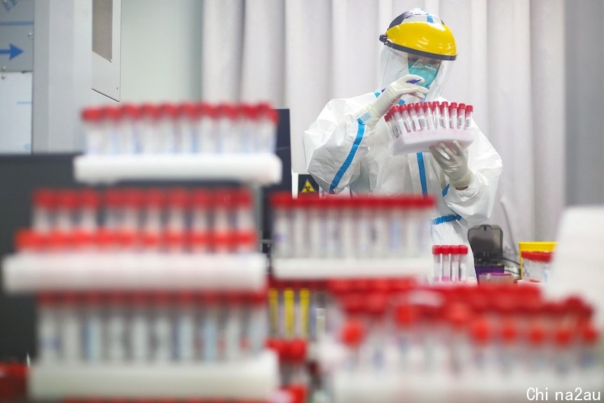 2021年7月24日，南京某医院一名穿戴个人防护装备的医务人员在检测实验室查看药瓶