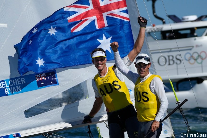 Two men sailing by their sailing boat celebrating after winning gold at the Olympics