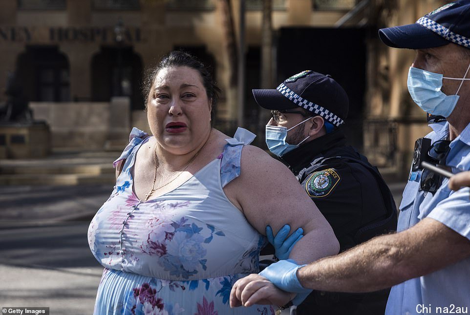 One protester in Sydney is seen being taken away in handcuffs by police on Tuesday