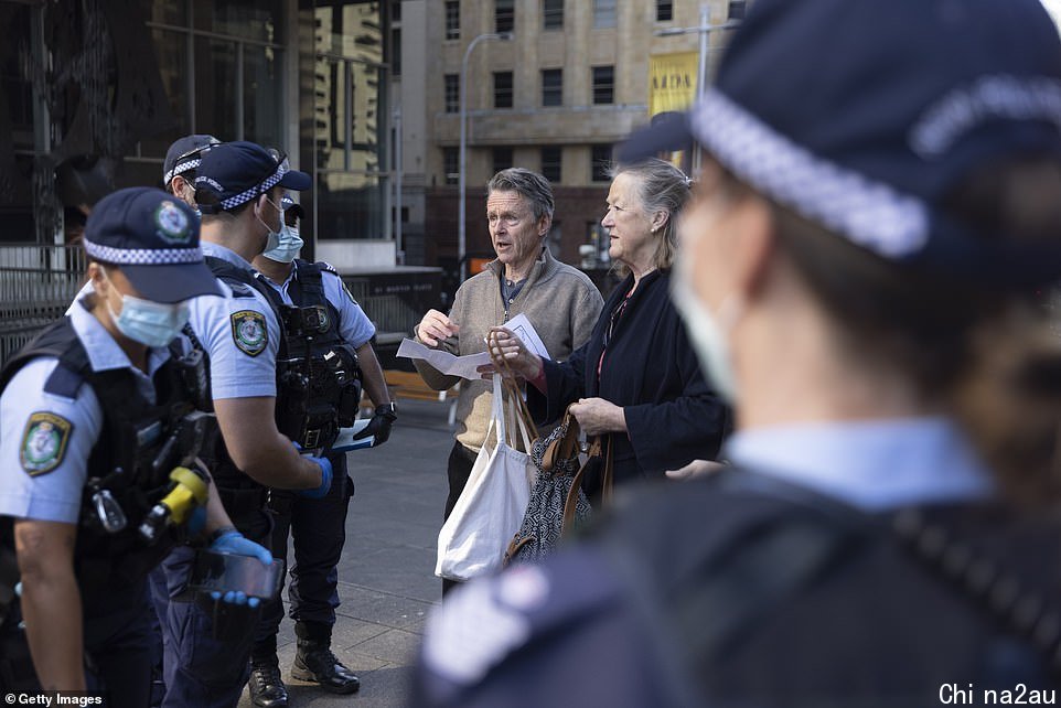 Police are seen speaking to a group of unmasked Sydneysiders at a silent protest on Macquarie Street