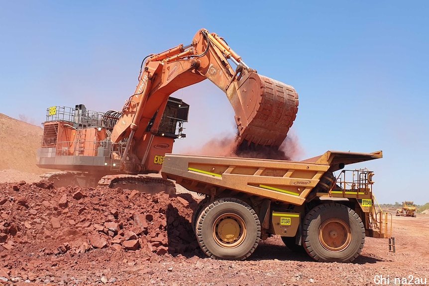 A digger is filling up a truck with iron ore in the NT.