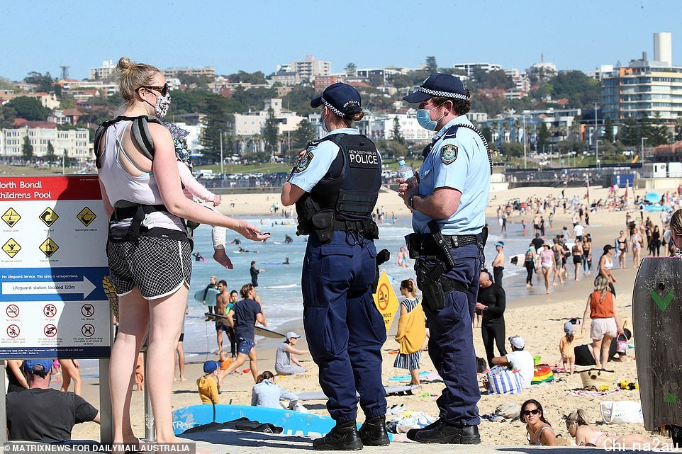A mother is seen speaking to police as thousands race to the beach in Bondi