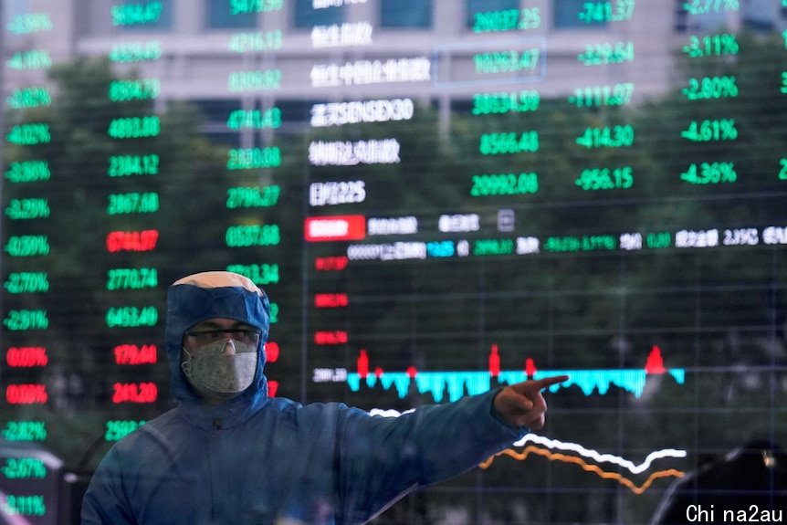 一名身穿蓝色防护服、头戴面罩和护目镜的男子站在证券交易所前。