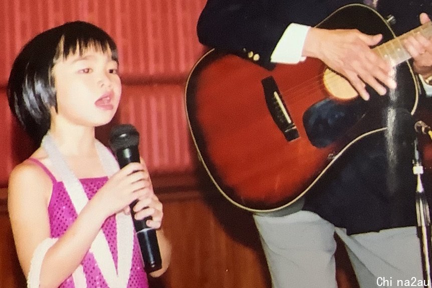 A little girl sings on stage.