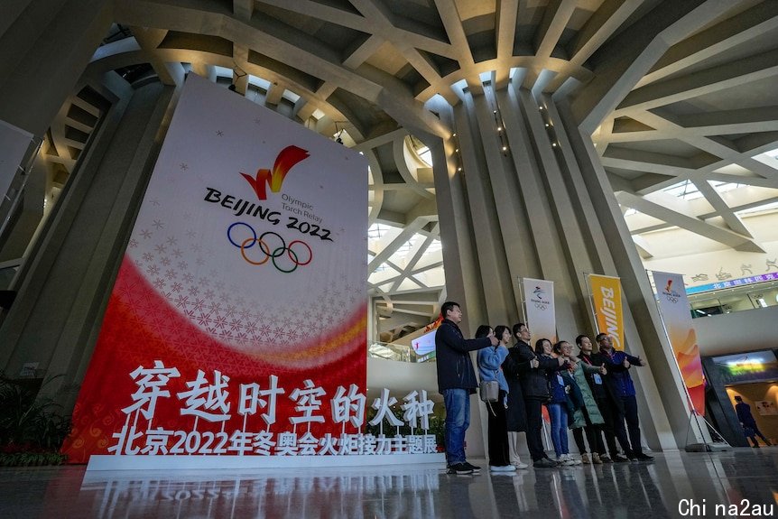 People pose near a Beijing 2022 Winter Olympic Games decoration