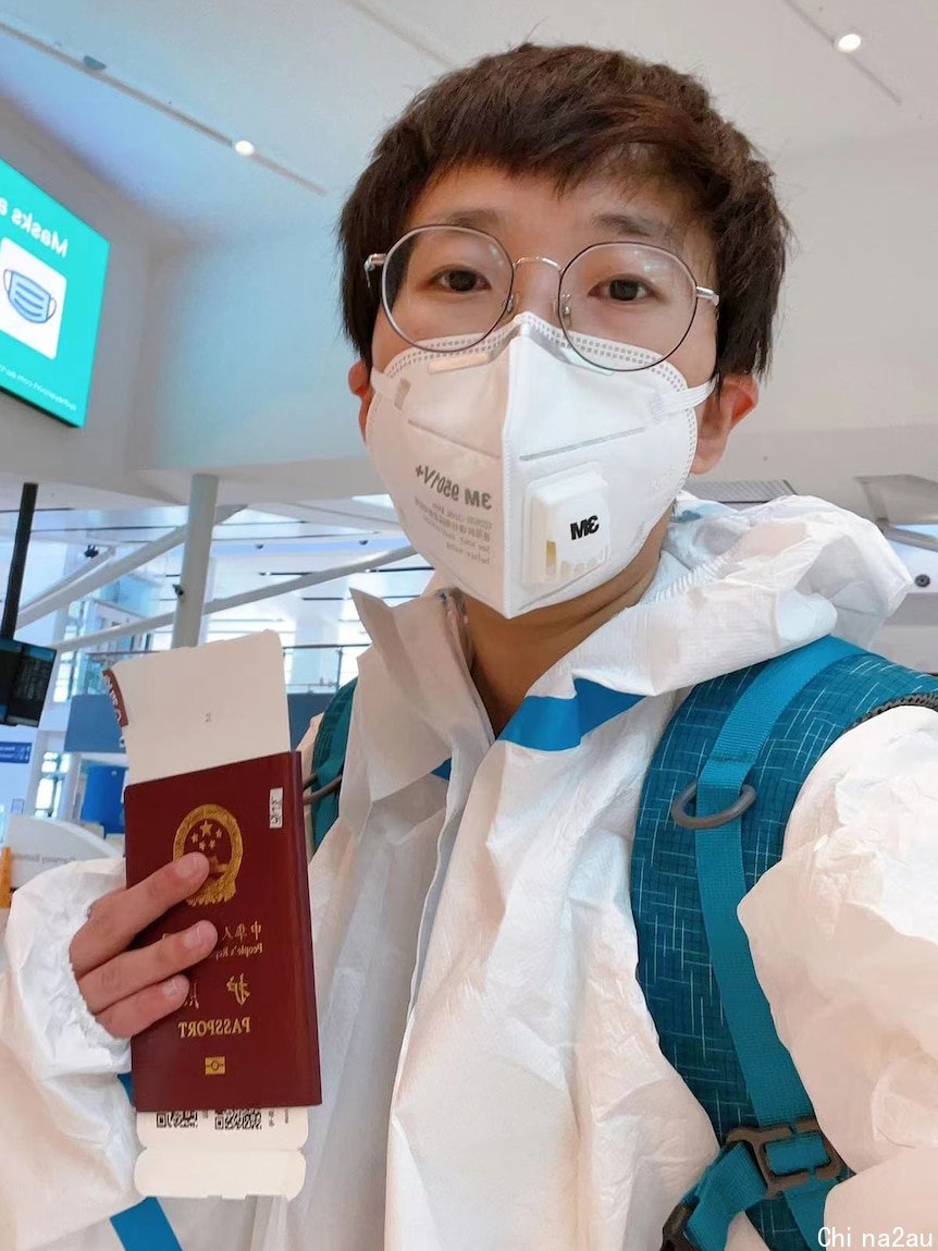 A young lady wearing glasses and mask holding a Chinese passport