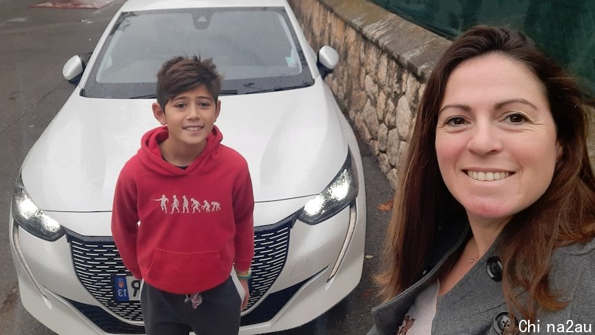 A brunette woman and a young boy before a new white car