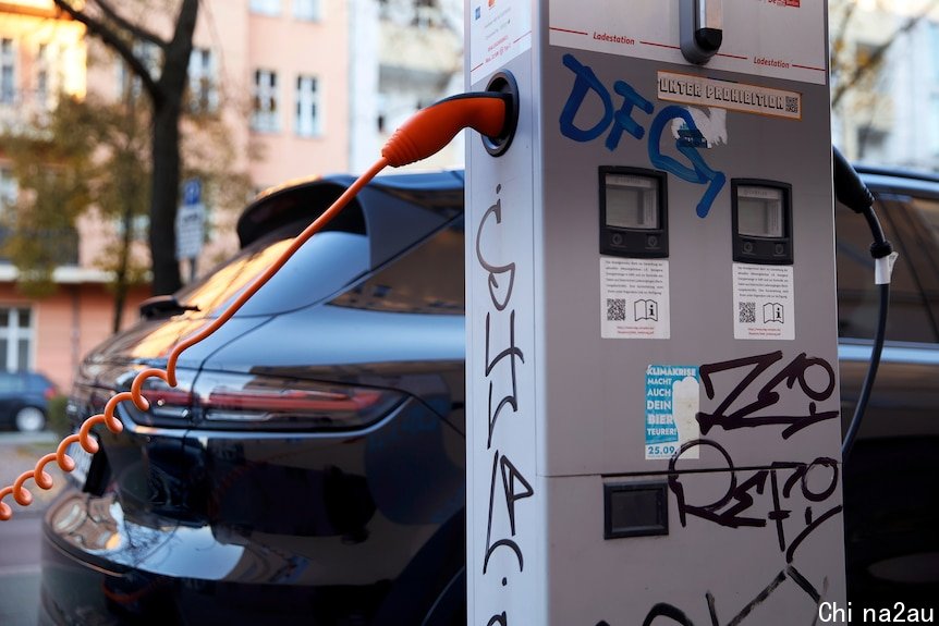 A roadside vertical box EV charger scrawled with graffiti tags