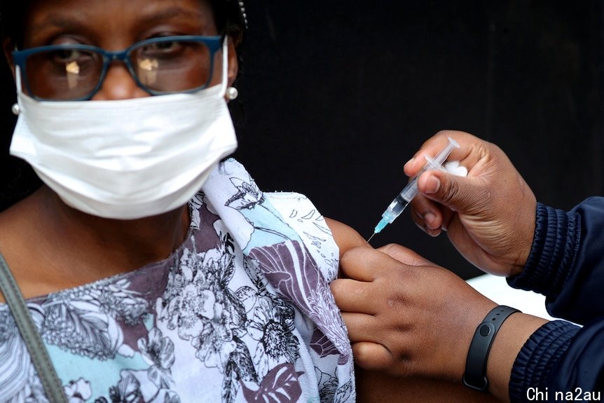Woman wearing glasses and white mask receives vaccination