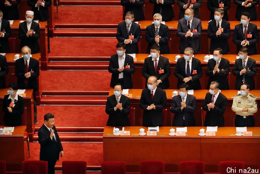 The parliamentary benches are lined with people wearing masks. Mr Xi, standing in front of them, does not