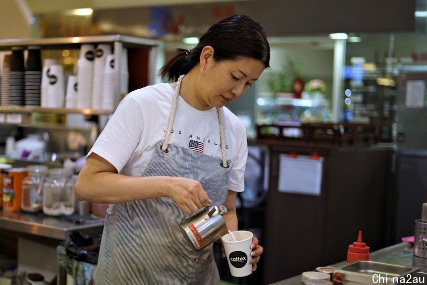 A woman in an apron makes a coffee.