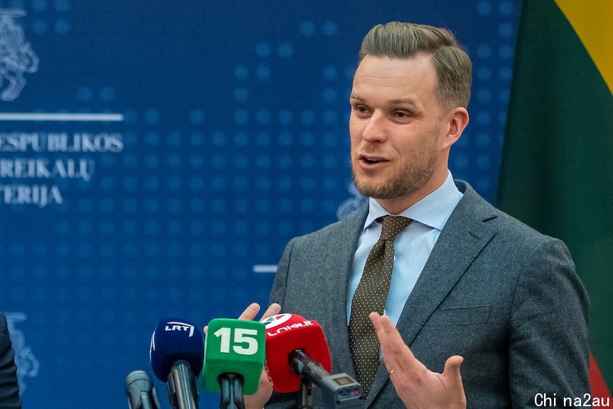 Two men standing in front of microphones in suits.