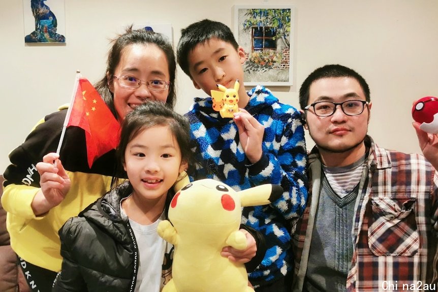 A couple and their two children pose with Pokemon figurines and a Chinese flag