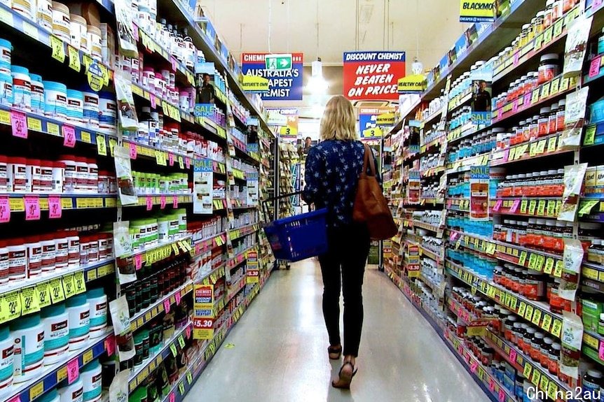 A woman walks down the aisle of a chemist