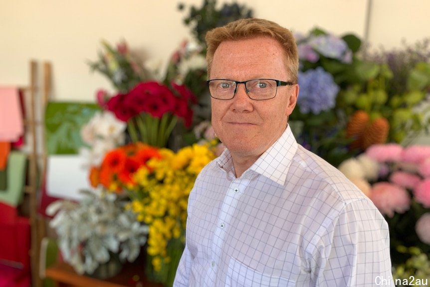 Interflora CEO Gerry Gerrard stands in a florist shop.