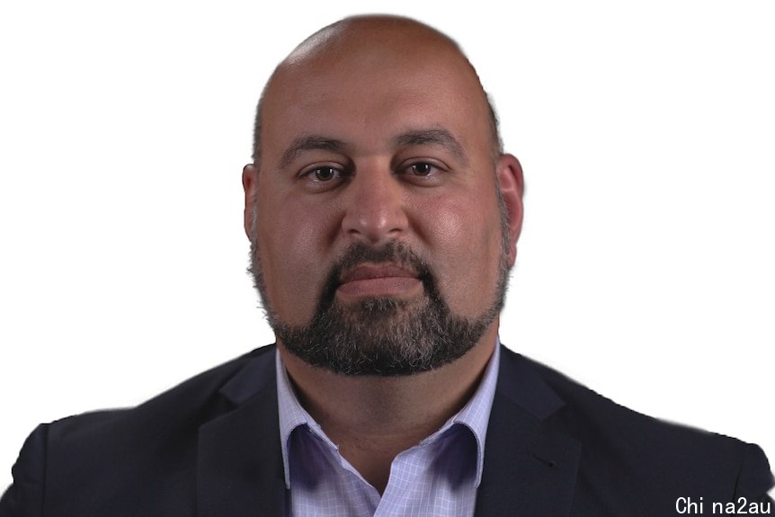 HEadshot of a man wearing a black suit jacket and button-up shirt against white background