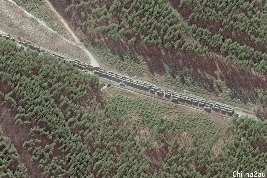 A long line of Russian vehicles on a road surrounded by forrest.
