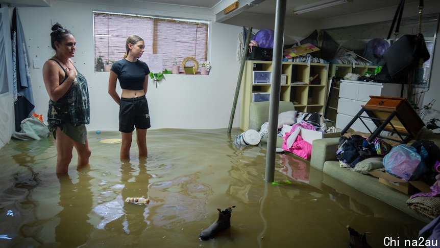 一个女人和一个女孩站在被水淹没的卧室里，脸上露出绝望的表情