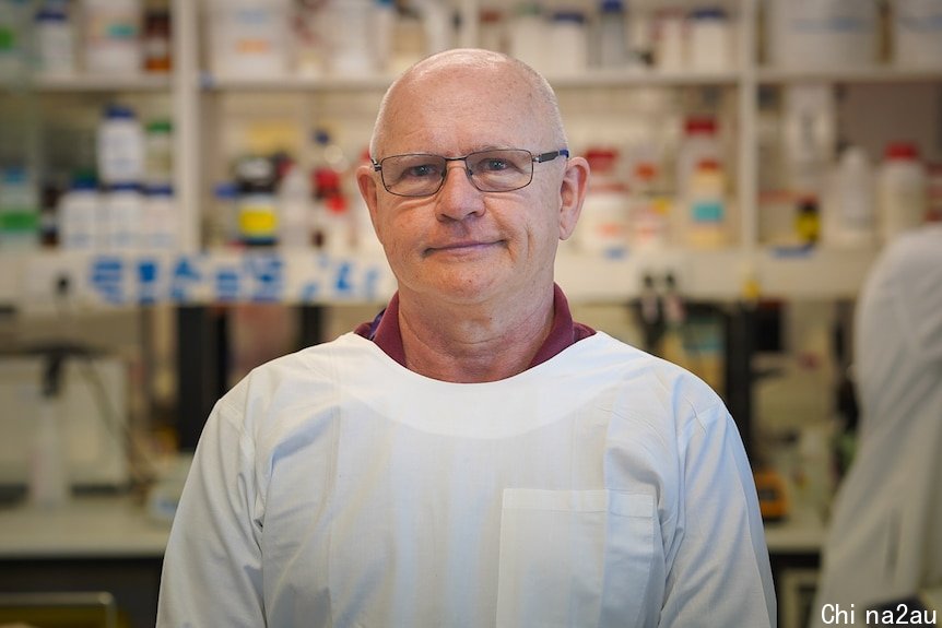 A professor in a lab wearing a white coat.