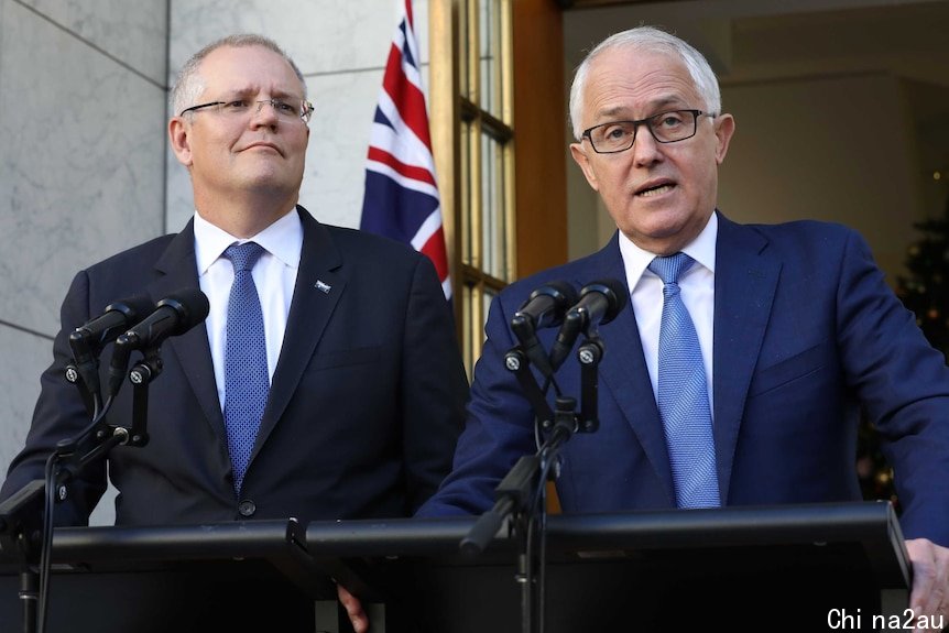 Scott Morrison and Malcolm Turnbull stand at two sets of microphones. Behind them is an Australian flag