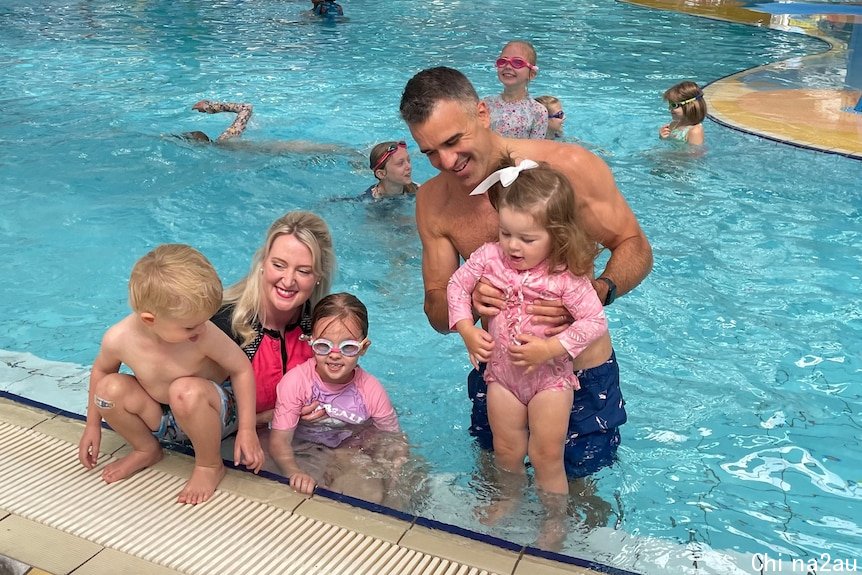 A man and a woman with three children in a pool