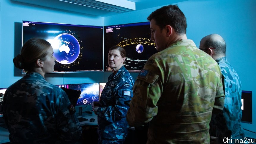 Four soldiers stand inside a dimly lit control room, with screens displaying planet Earth and orbiting satellites.