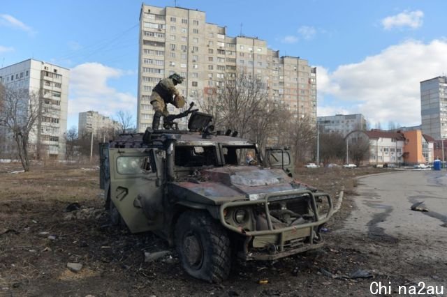 A Ukrainian territorial defence soldier examines a burnt-out Russian army vehicle in Kharkiv