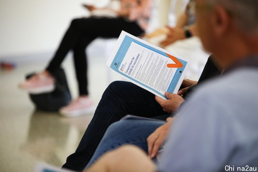 A person holds a COVID-19 vaccination consent form.