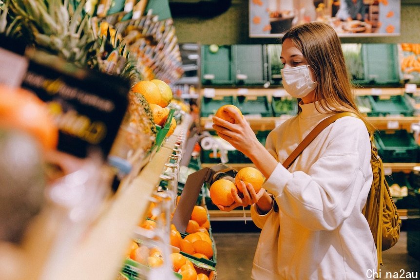 A woman wearing a face mask grocery shops. 