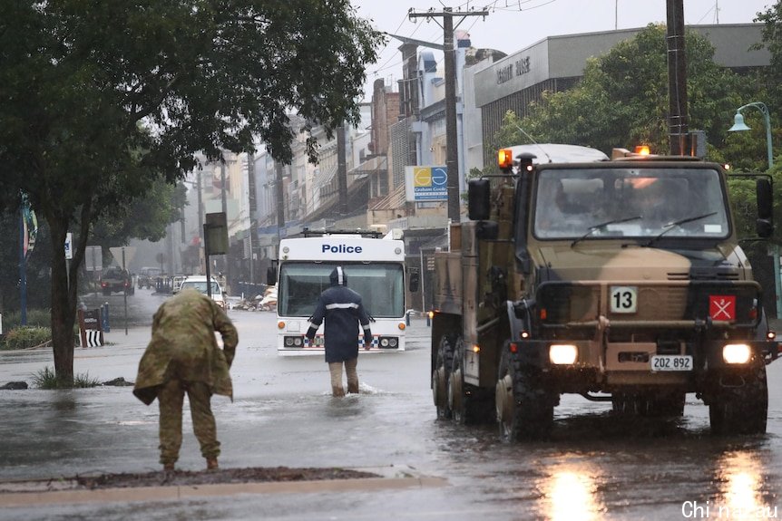 Military people look at flood waters.