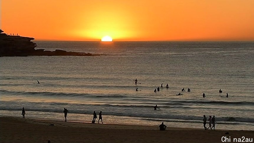 The sun rising above the horizon at Bondi Beach.