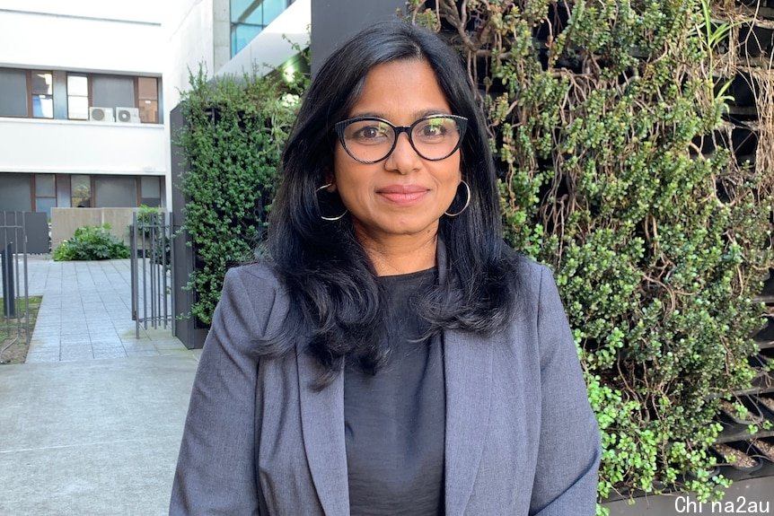 Dr Nusrat Homaira is wearing a blazer and glasses and standing outside
