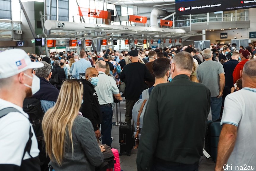 People wearing masks and carrying bags line up in long queues