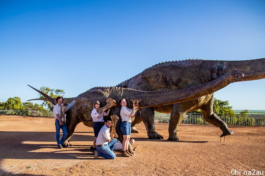 Dinosaur with people standing with skeleton pieces