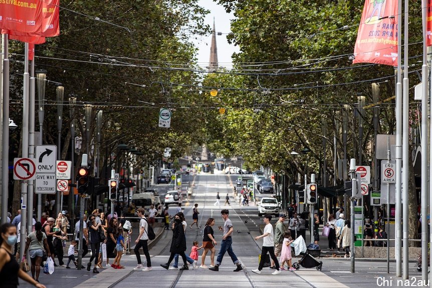 Pedestrians, some masked and some not, cross Bourke Street mall during the day.