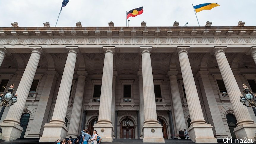 A group sits on the stairs in front of Victoria's parliament house.