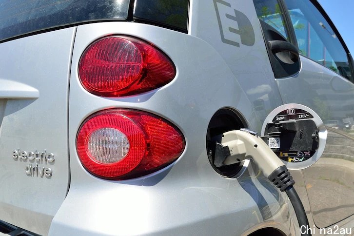 A close-up photo of an electric vehicle charging at a port. 