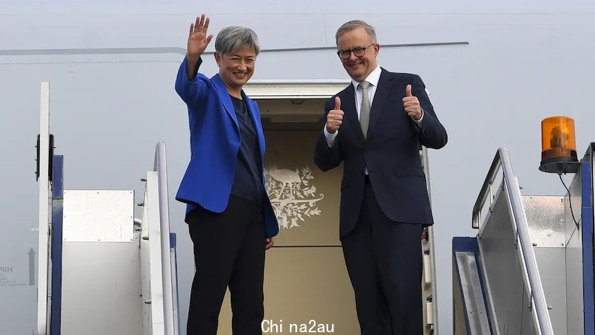 Anthony Albanese and Penny Wong wave to the press pack before boarding plane