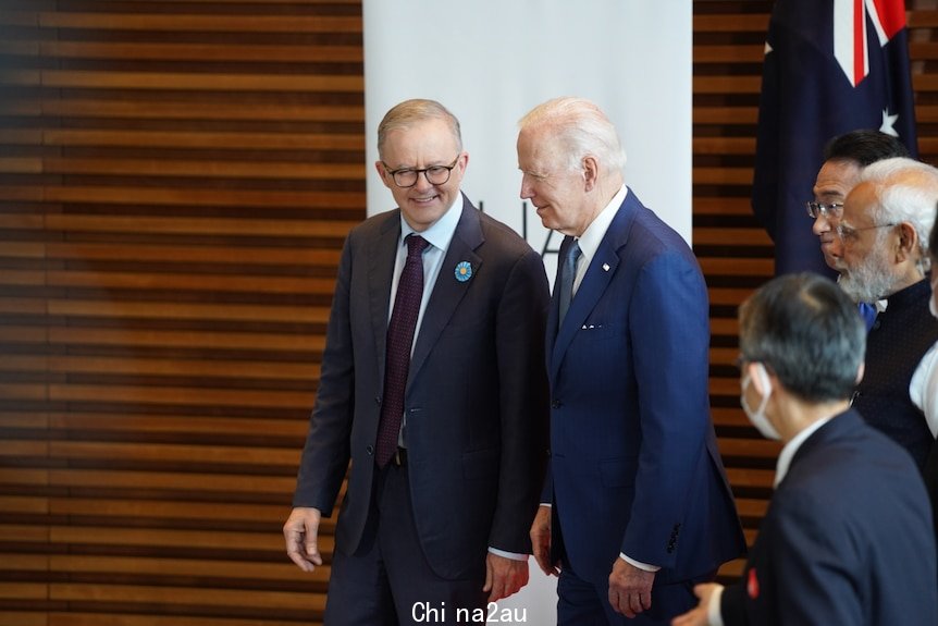 Two men in suits talk to eavch other.