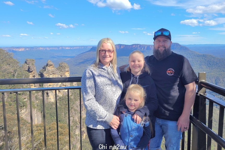 Family of four standing on a lookout with mountains in the background