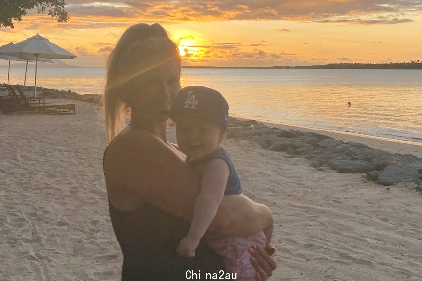 Woman with baby and sunset and beach in background