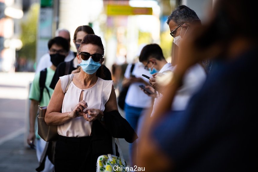 戴着口罩和墨镜排队接种疫苗的女士