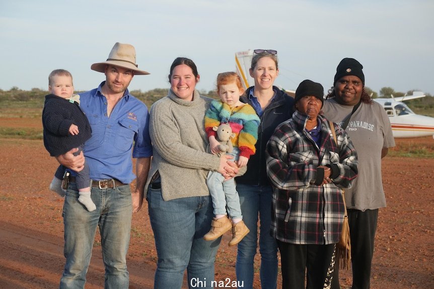 A family and visitors standing in front of a plane in outback NSW.